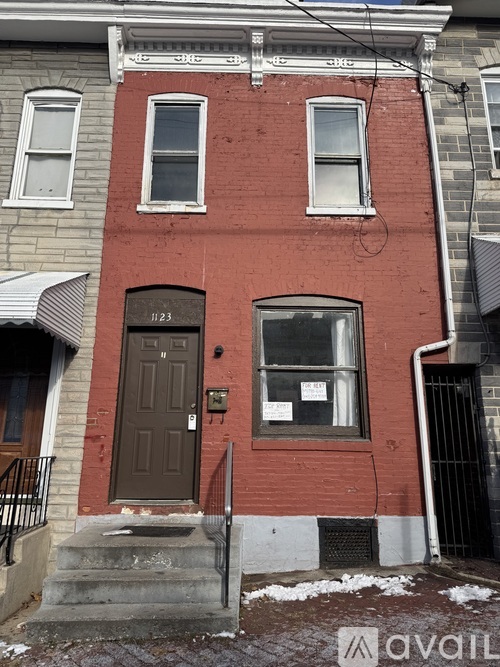 A red brick building with a black door and a window with a sign on it.