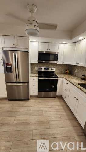 A kitchen with white cabinets and a stainless steel refrigerator.