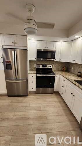 A kitchen with white cabinets and a stainless steel refrigerator.