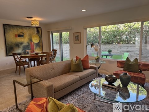 A living room with a couch, chairs, and a painting on the wall.