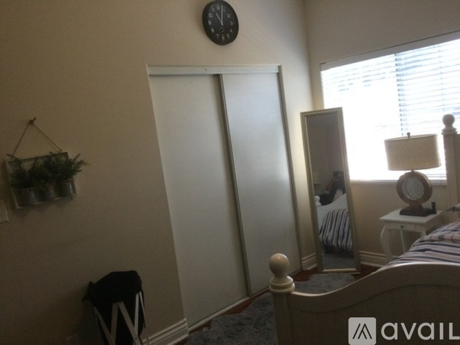 A bedroom with a bed, dresser, mirror, and a plant.