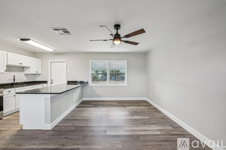 A spacious kitchen with white cabinets and a wooden floor.