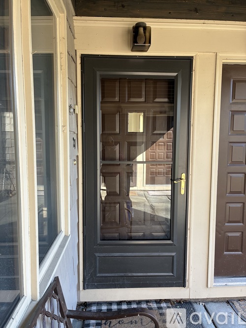 A black door with a gold handle is in the middle of a white wall.