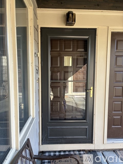 A black door with a gold handle is in the middle of a white wall.