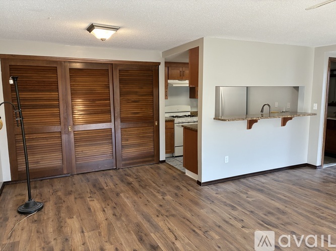 A room with wooden floors and a white wall with a bar area.