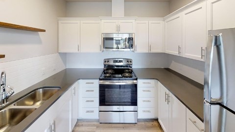A modern kitchen with white cabinets and stainless steel appliances.