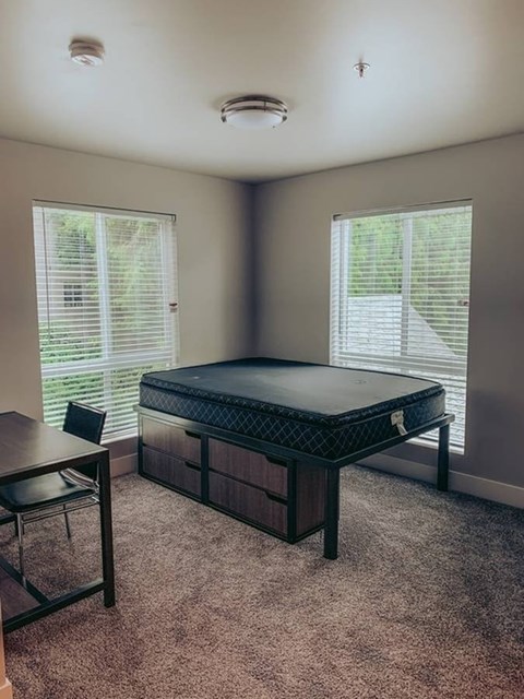 A bedroom with a bed, desk, and chair.