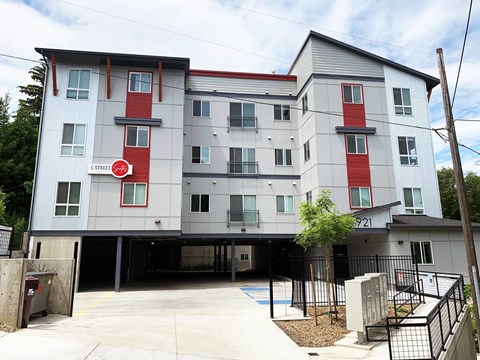 A modern apartment building with a red and white sign on the front.