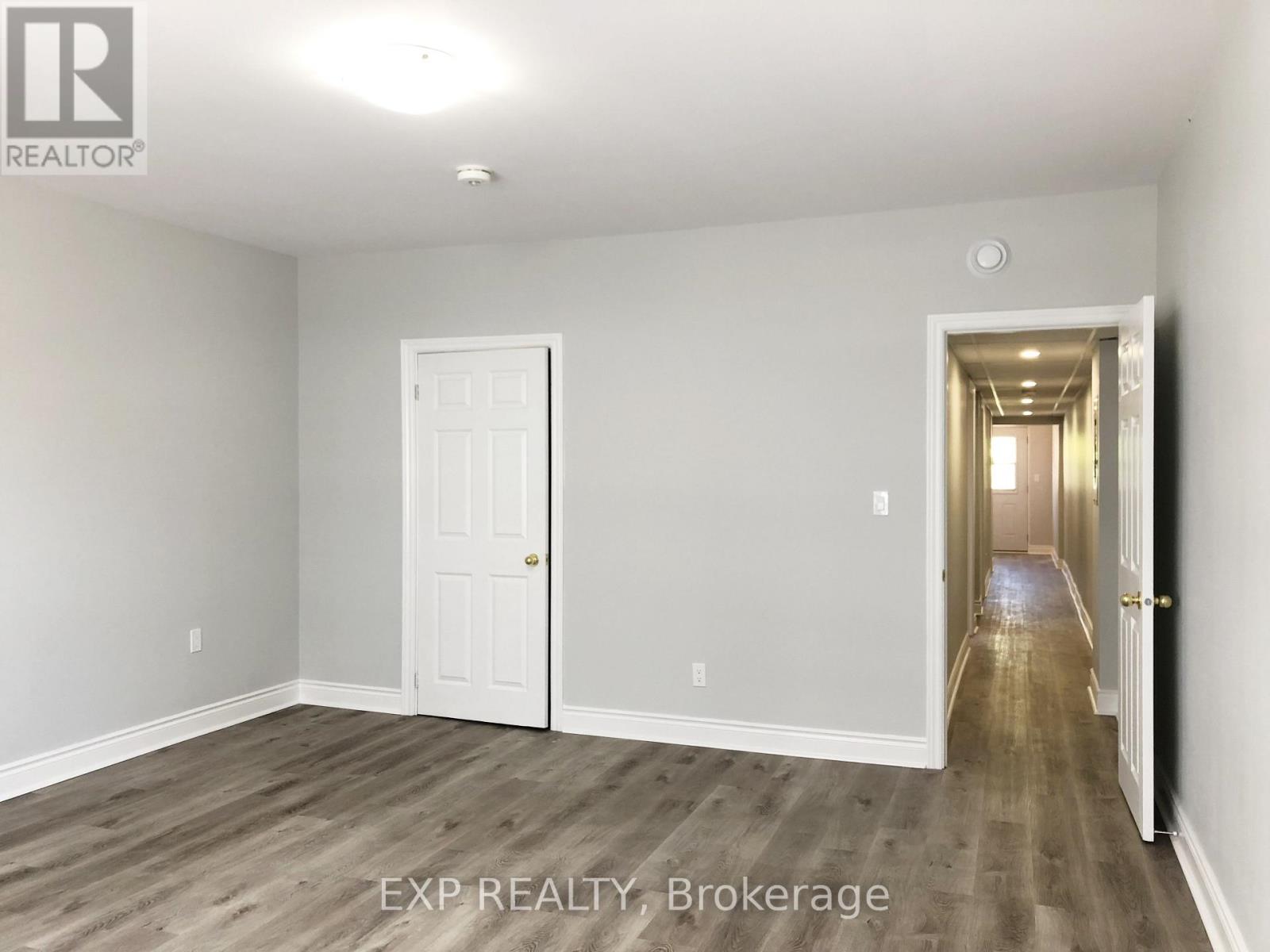 A room with a white door and a hallway leading to another room.