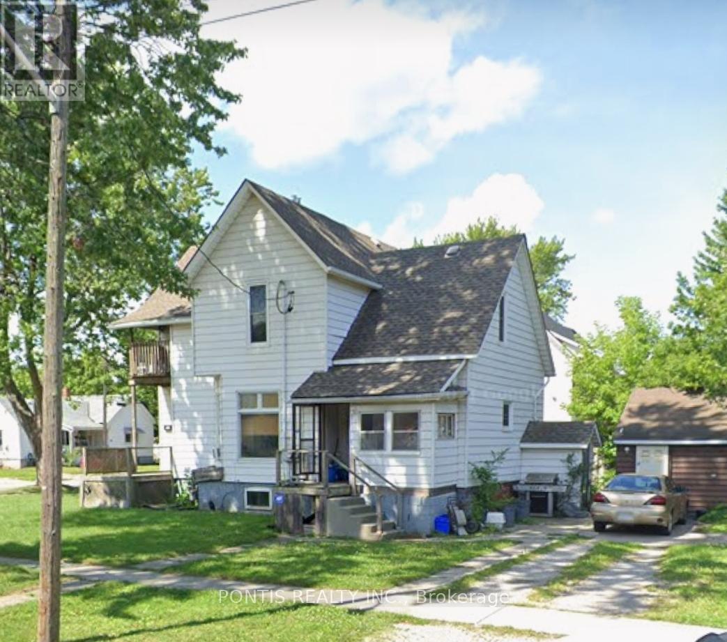 A white house with a porch and a car parked in front.