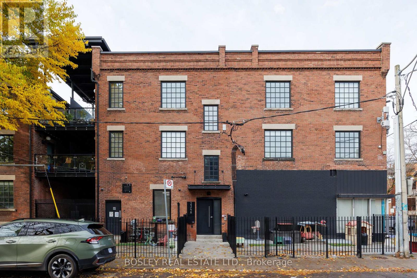 A building with a black facade and a tree with yellow leaves in front of it.