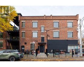 A building with a black facade and a tree with yellow leaves in front of it.