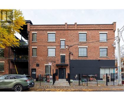 A building with a black facade and a tree with yellow leaves in front of it.