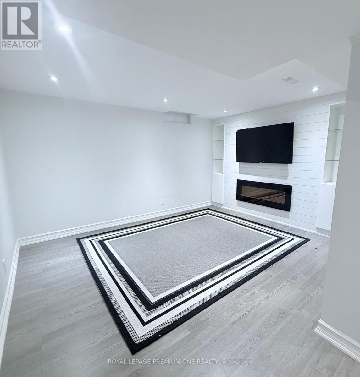 A living room with a fireplace and a flat screen TV mounted on the wall.