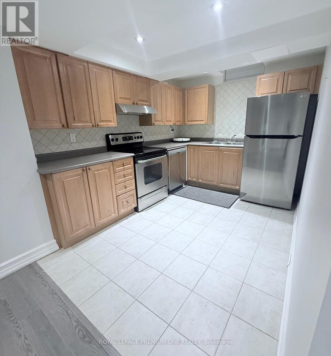A kitchen with wooden cabinets and a stainless steel refrigerator.