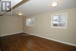 A room with wooden floors and two windows.