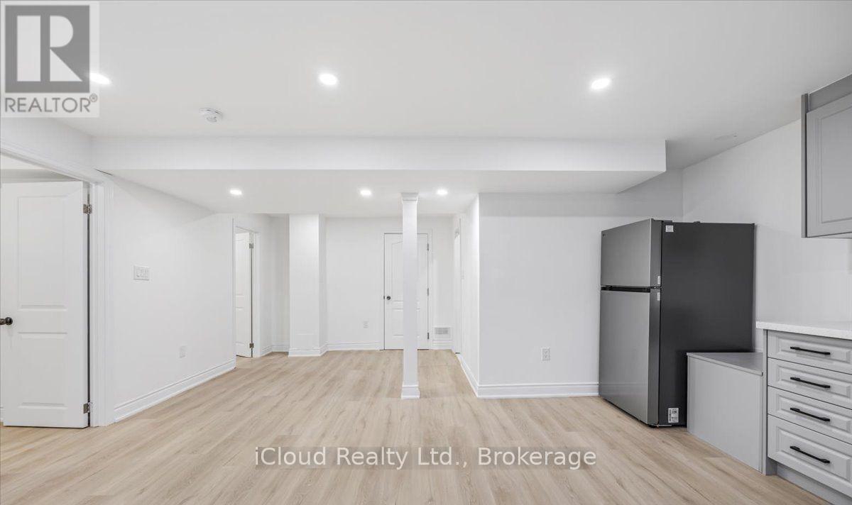 A spacious, empty room with a refrigerator and a cabinet.
