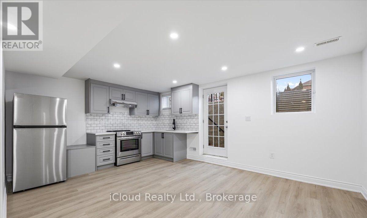 A modern kitchen with stainless steel appliances and wooden flooring.