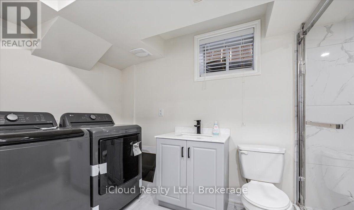 A small, white bathroom with a toilet, sink, and a window with blinds.