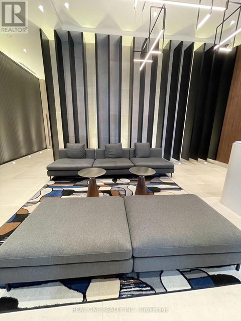A modern living room with a grey sofa and a patterned rug.