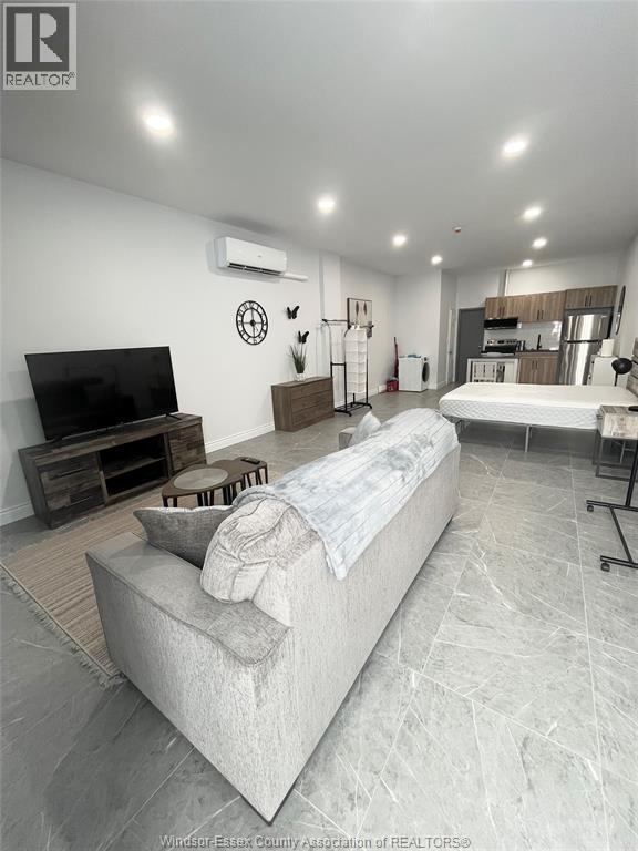 A living room with a couch, television, and a wall clock.