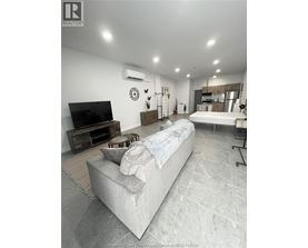 A living room with a couch, television, and a wall clock.