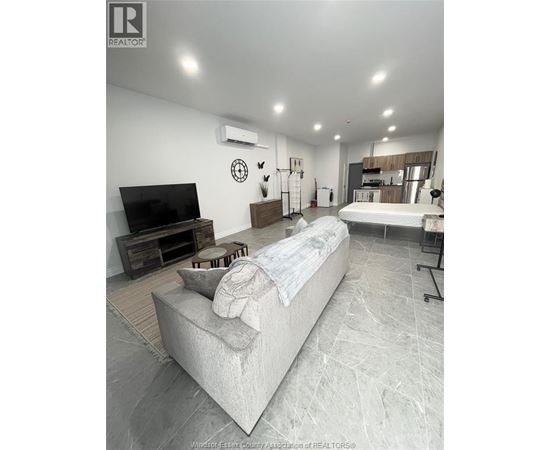 A living room with a couch, television, and a wall clock.
