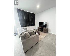 A living room with a grey couch, a television, and a wooden coffee table.