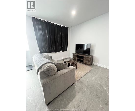A living room with a grey couch, a television, and a wooden coffee table.