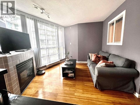 A living room with a grey couch and a fireplace.