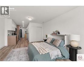 A bedroom with a bed covered in a blanket and a lamp on a side table.