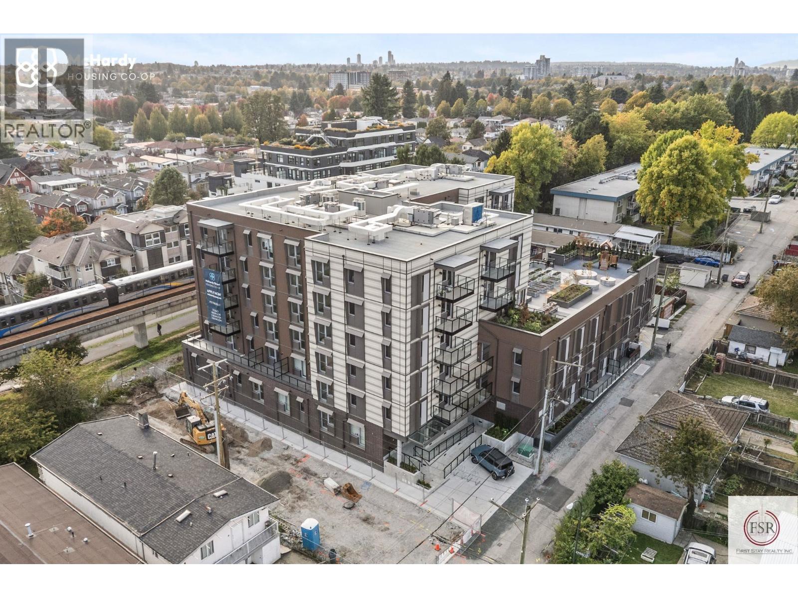 A construction site with a building under construction in the foreground and a residential area in the background.