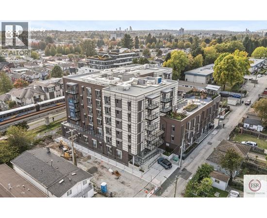 A construction site with a building under construction in the foreground and a residential area in the background.