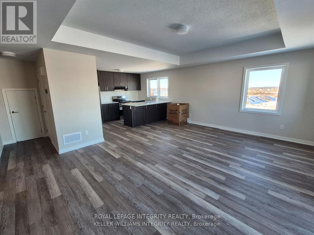 A room with wooden flooring and a window showing a view of a parking lot.