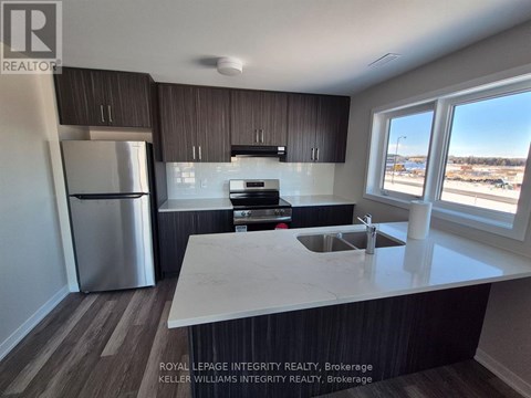 A kitchen with a white counter top and a stainless steel refrigerator.