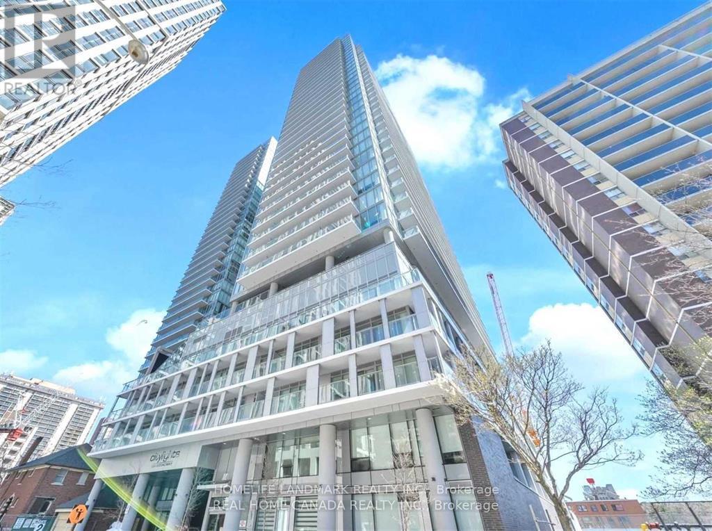 A tall building with a glass facade stands in the foreground of a cityscape.