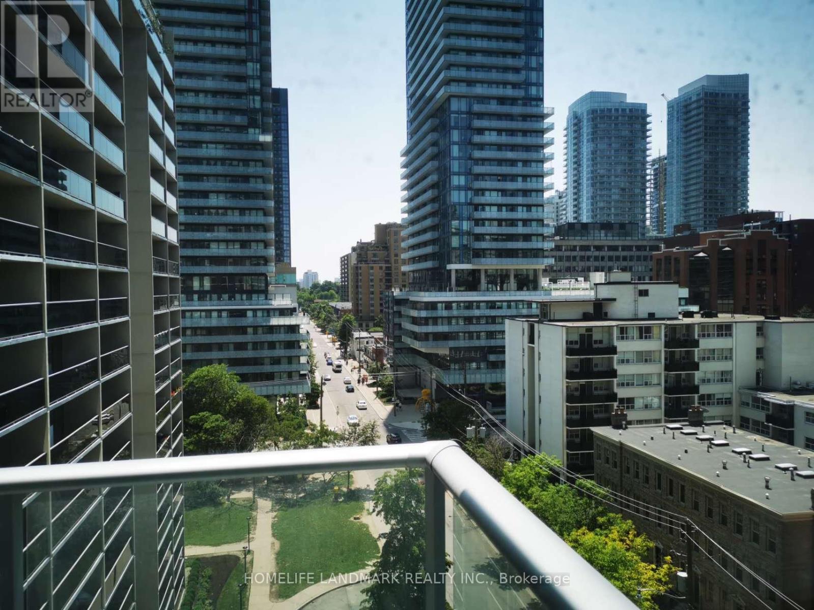 A view of a city from a balcony with buildings and a road.