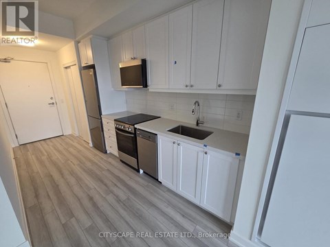 A kitchen with white cabinets and a wooden floor.