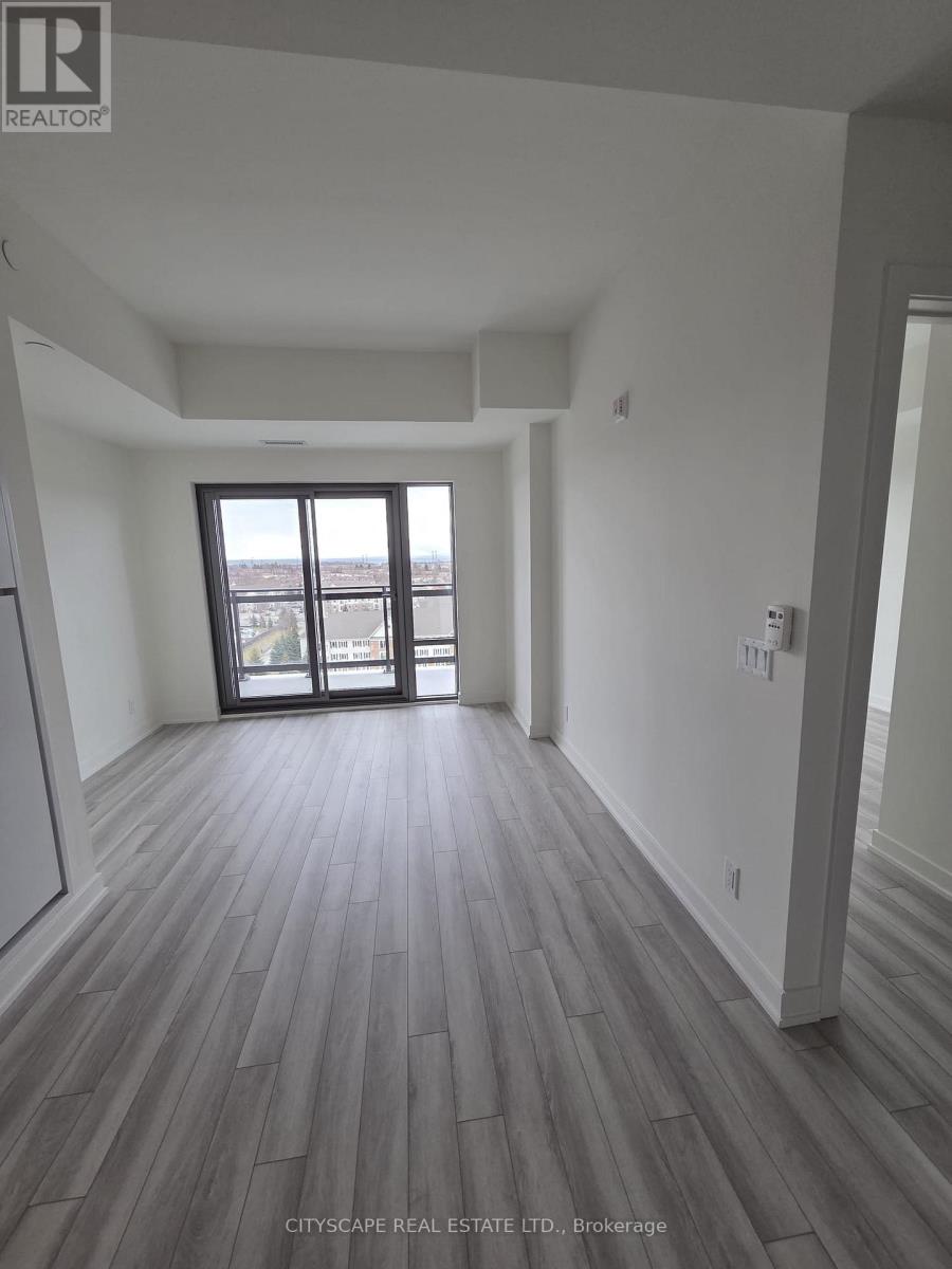 A spacious room with wood flooring and a large window.