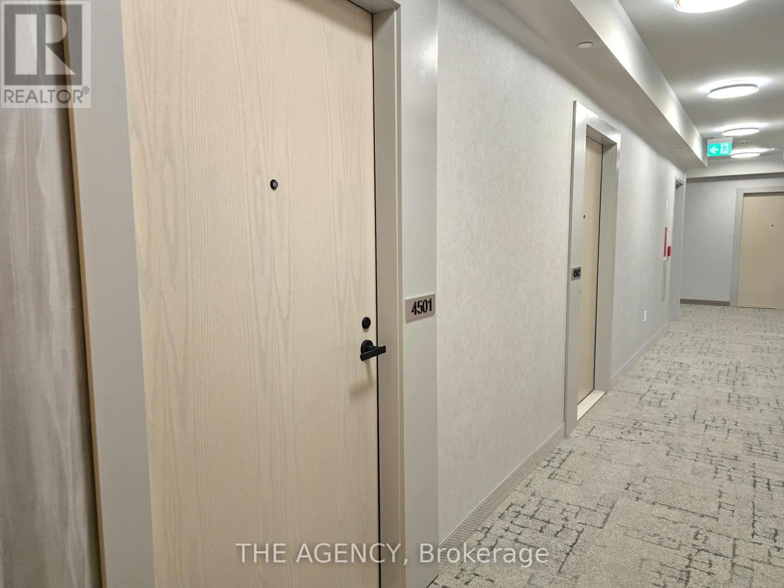 A hallway with a door on the left and a brokerage agency on the right.