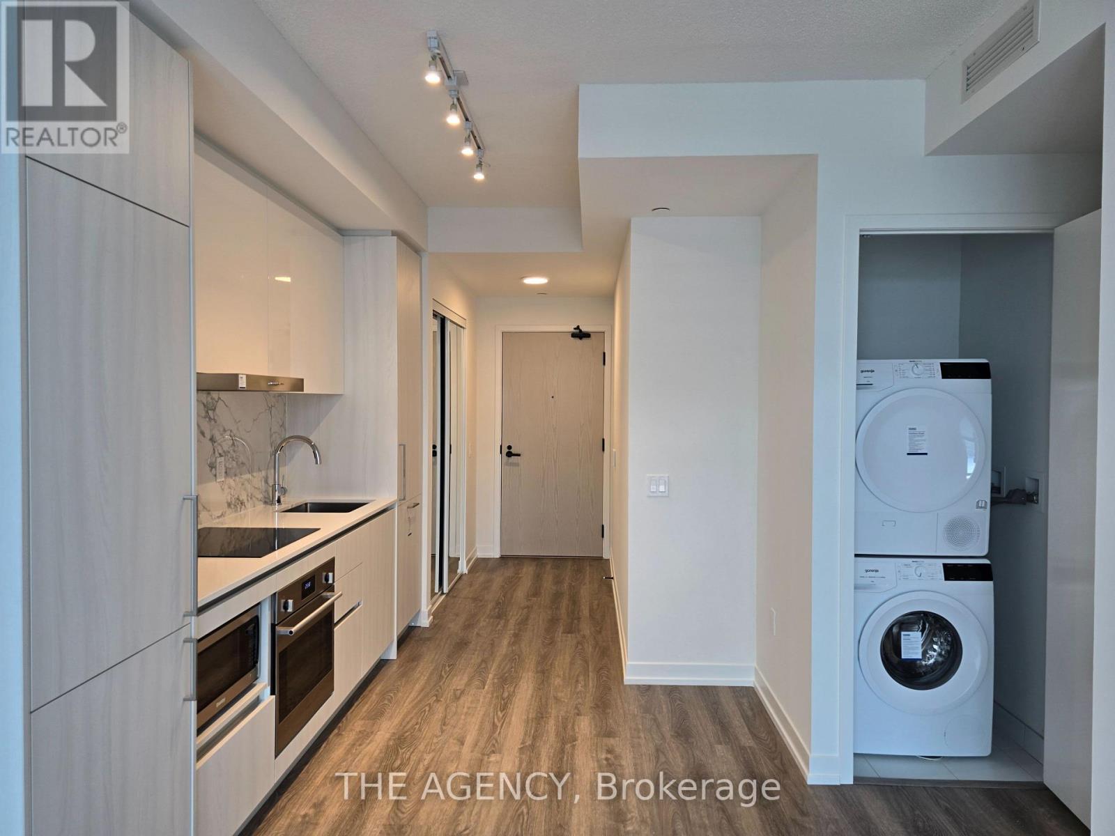 A modern kitchen with a washing machine in the corner.