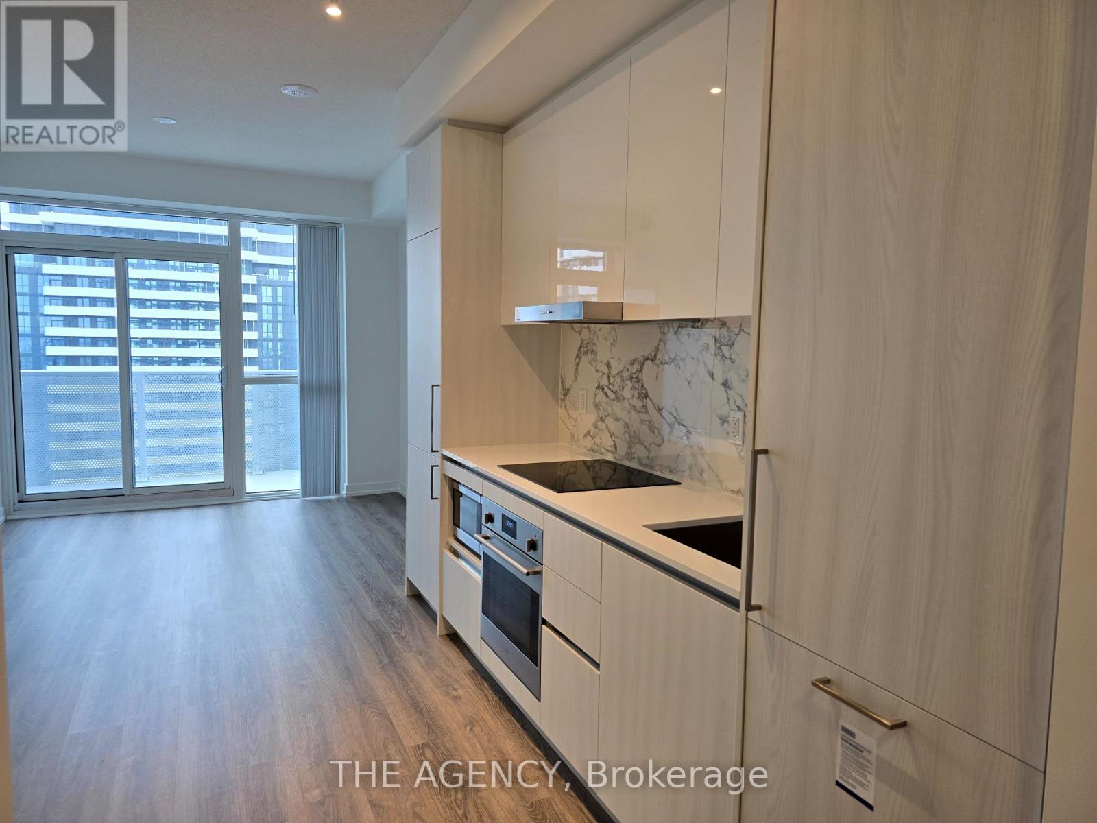 A kitchen with wooden cabinets and a marble backsplash.