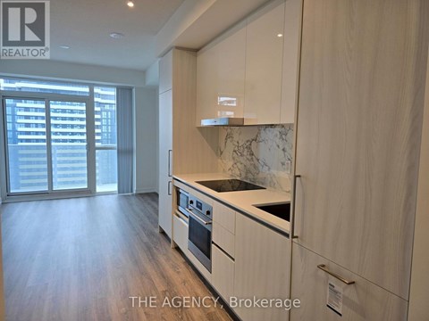 A kitchen with wooden cabinets and a marble backsplash.