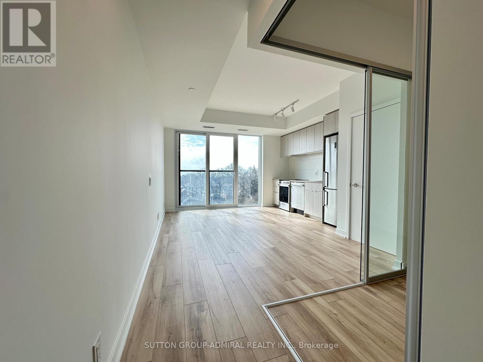A spacious room with wooden flooring and a glass door leading to a balcony.