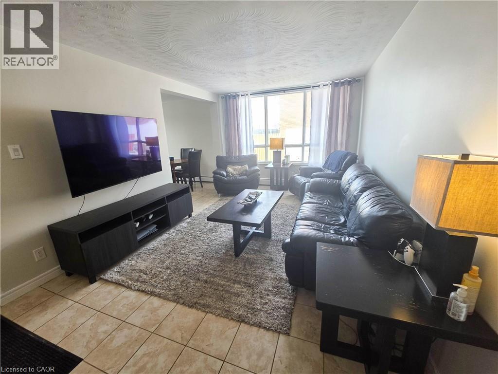 A living room with a black leather couch and a flat screen TV.