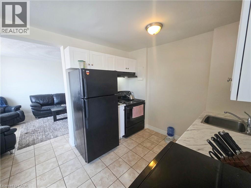 A black refrigerator in a kitchen with a sink and a counter.