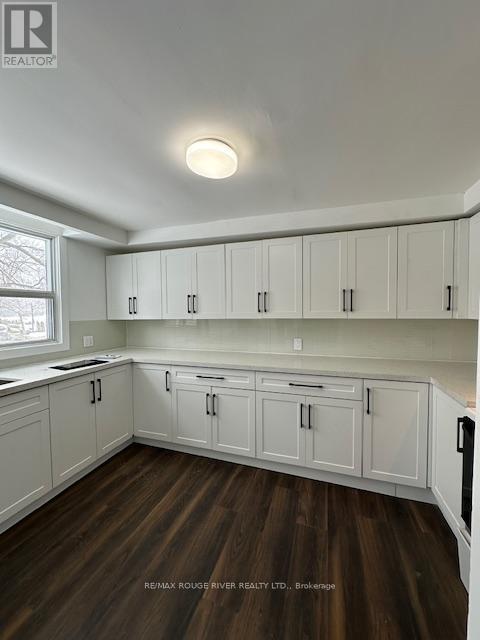 A kitchen with white cabinets and wooden floors.