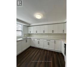 A kitchen with white cabinets and wooden floors.