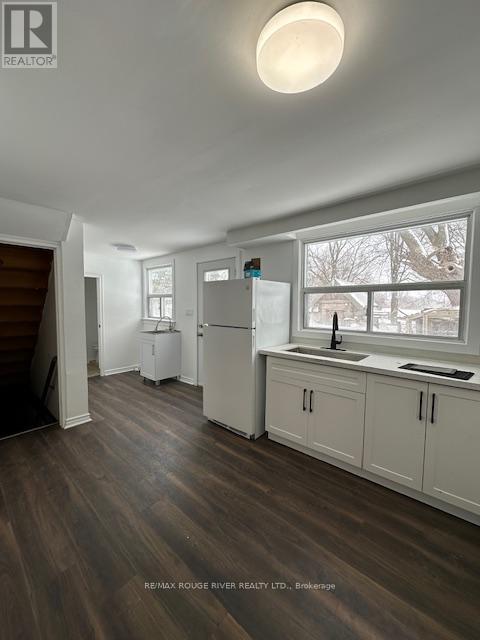 A kitchen with white appliances and wood floors.