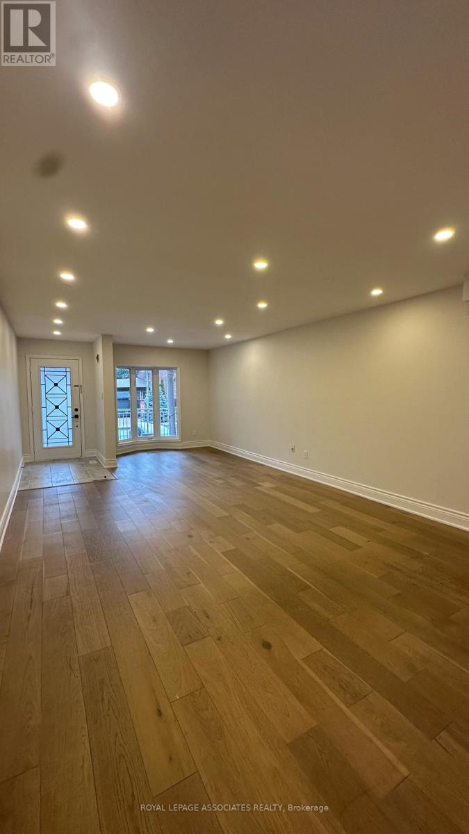 A spacious room with wooden flooring and recessed lighting.